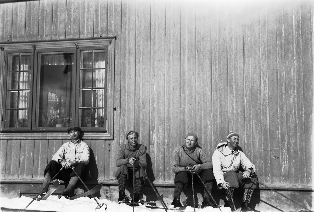 Håkon Prestkværn, Fire ukjente menn med nikkers og ski soler seg i husveggen.