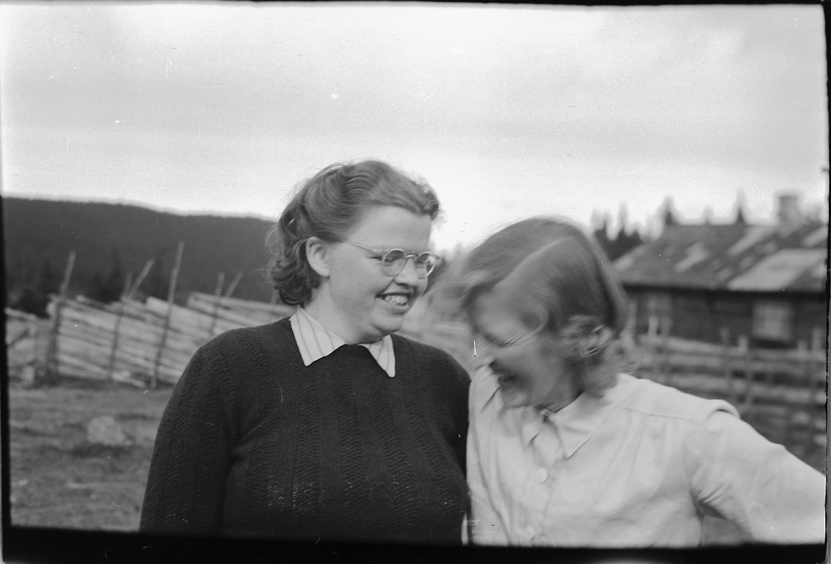 Håkon Prestkværn, To ukjente kvinner foran en skigard og ei hytte.