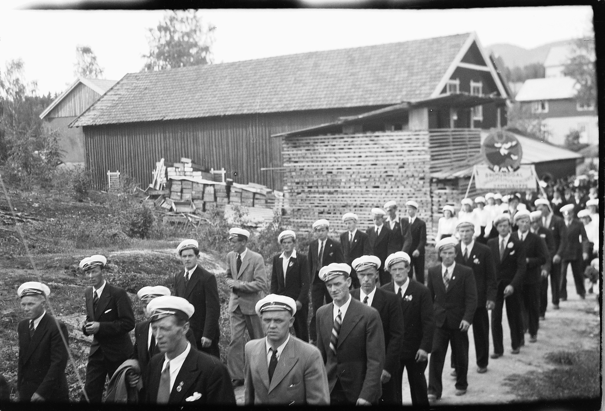 Håkon Prestkværn, Mannskor marsjerer. Ringsaker sang- og musikklagsstevne, Moelv 1948. Friluftskonserten i Folkets Hus park. Oppmarsj i Parkvegen forbi Johansens trevarefabrikk
