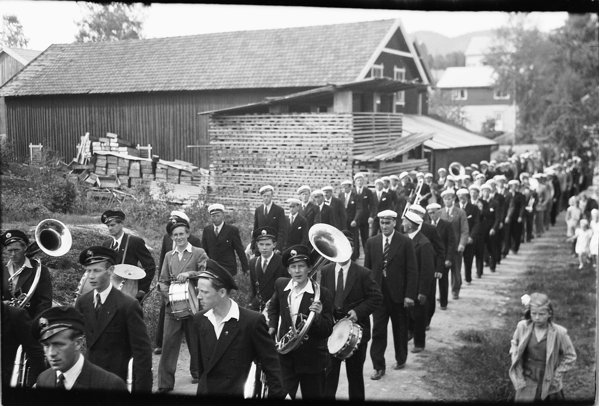 Håkon Prestkværn, Musikkorps og kor marsjerer. Ringsaker sang- og musikklagsstevne, Moelv 1948. Friluftskonserten i Folkets Hus park. Oppmarsj i Parkvegen forbi Johansens trevarefabrikk