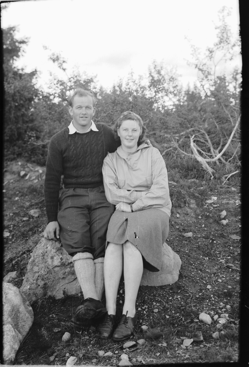 Håkon Prestkværn, Ukjent mann og kvinne sitter på en stein i skogen.