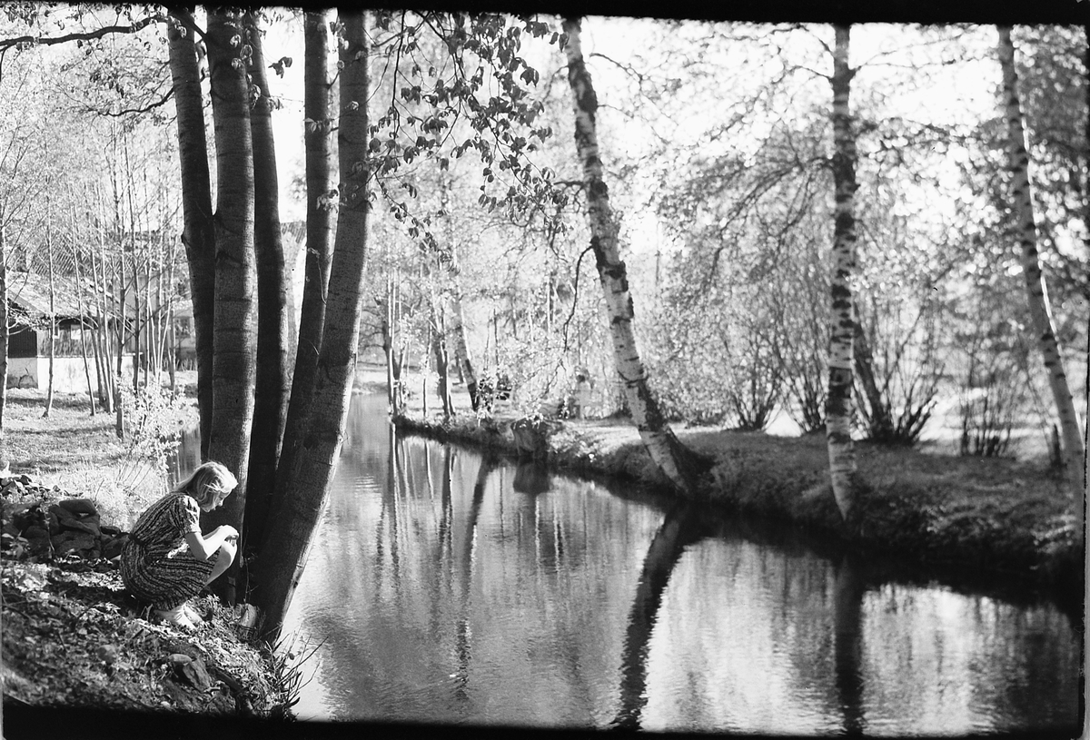 Håkon Prestkværn, Kvinne sitter på huk ved elvebredden.