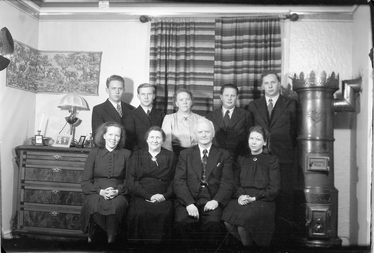 Håkon Prestkværn, Interiør, stue med ovn. Ukjent familiegruppe.