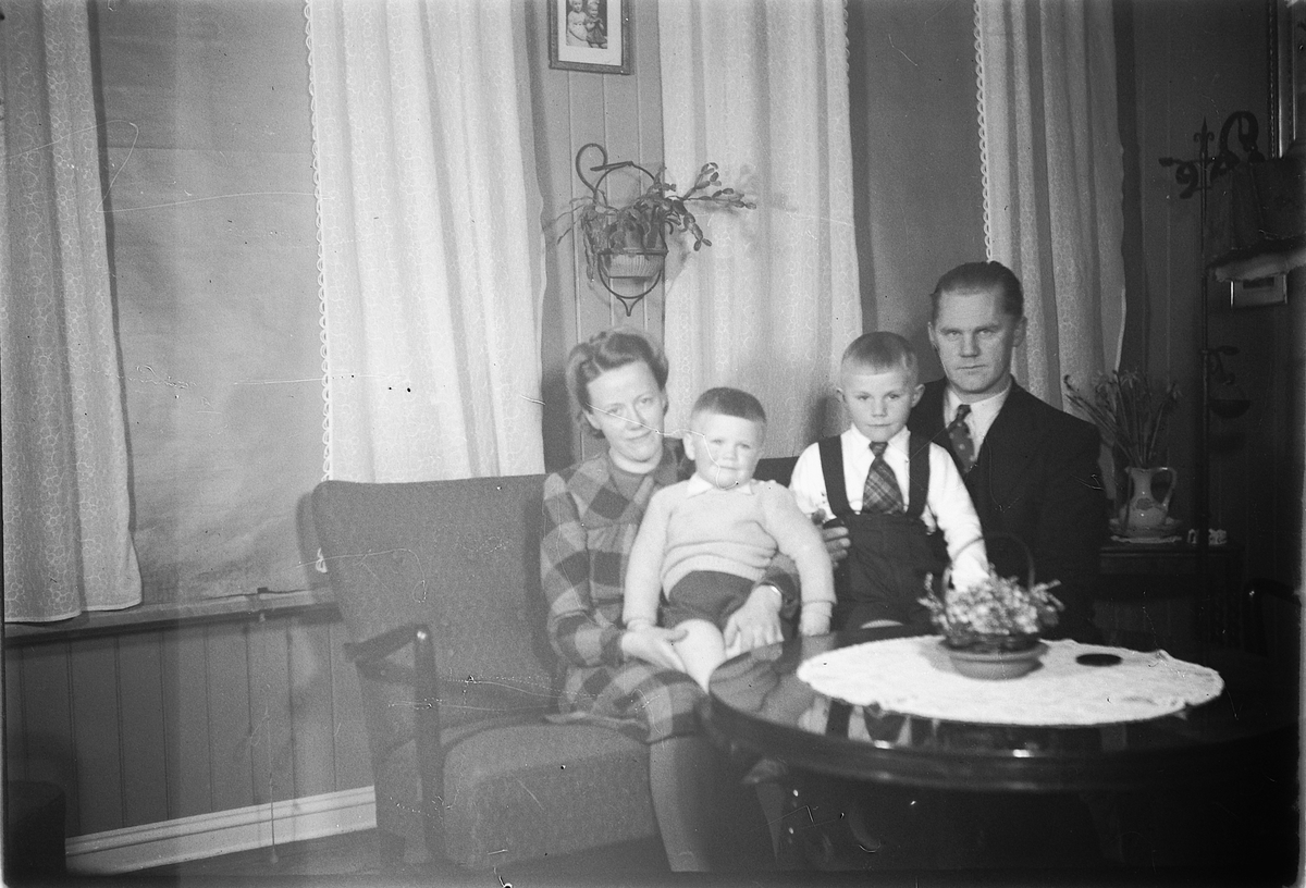 Håkon Prestkværn, Interiør, stue. Ukjen familie i sofaen.