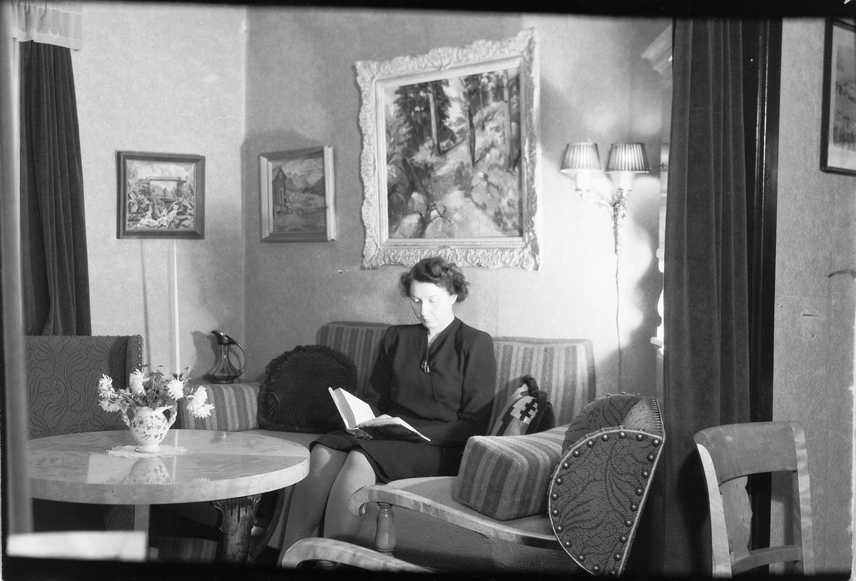 Håkon Prestkværn, Interiør, stue. Ukjent kvinne sitter i sofa og leser. Fotokonvolutt mrk. "Grensen jan. 1949"