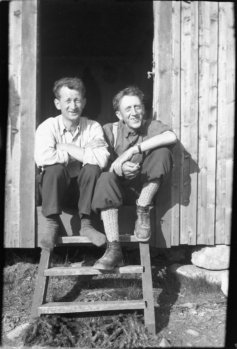 Håkon Prestkværn, To ukjente menn i inngangsdøra til et hus.