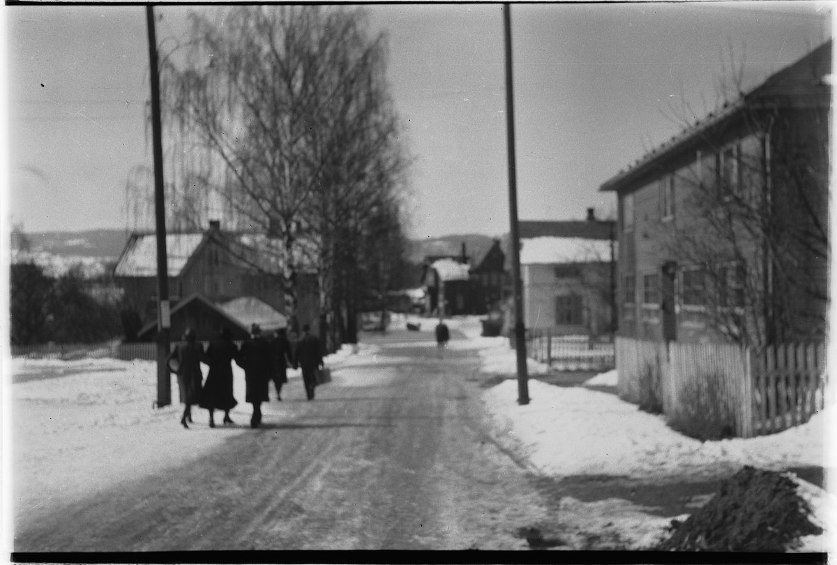 Håkon Prestkværn, Menn og kvinner med kofferter. Langs Åsmarkvegen i Moelv, mot stasjonen.