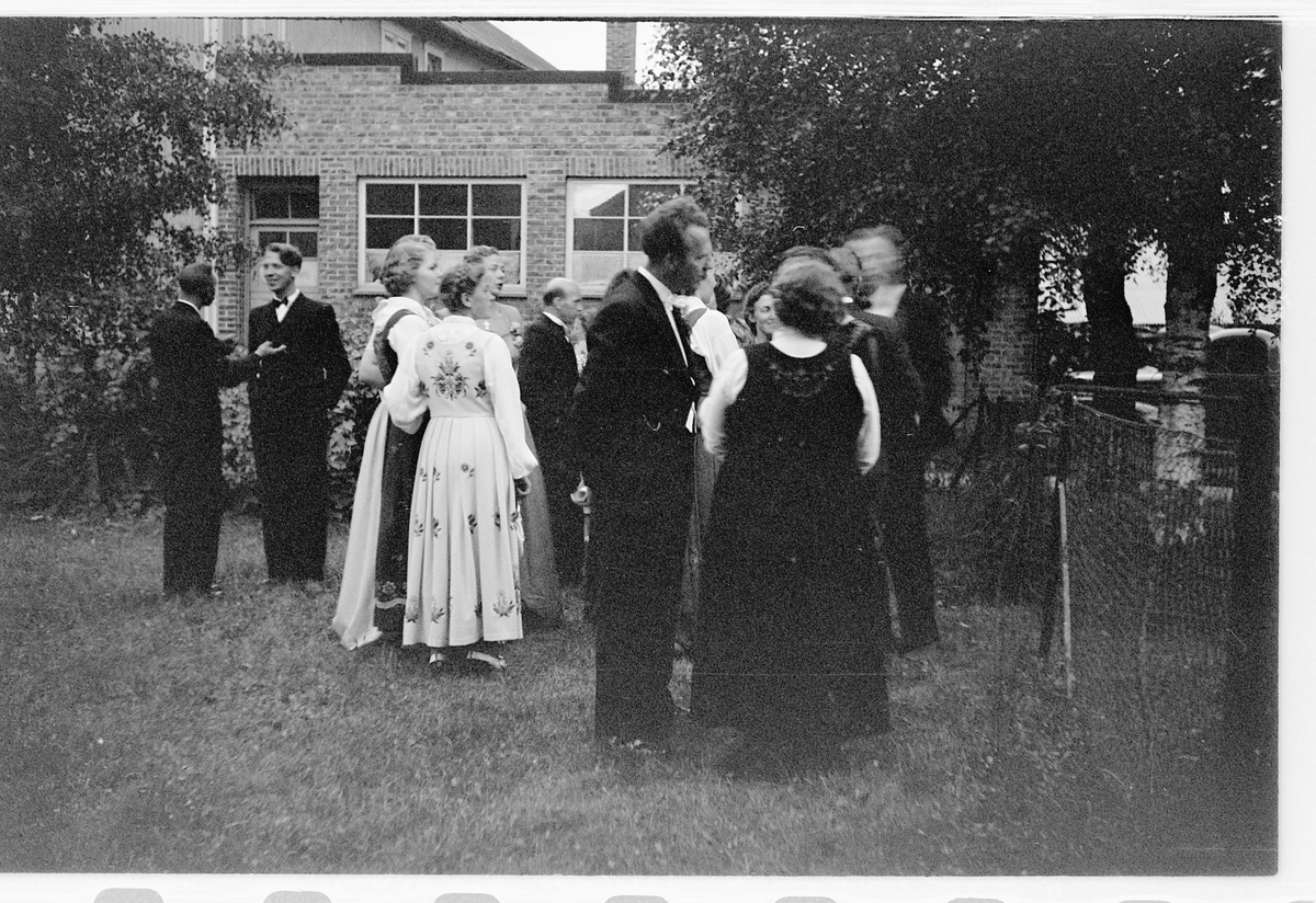 Håkon Prestkværn, Gruppe kvinner og menn i bunad og dress samlet i en hage.
