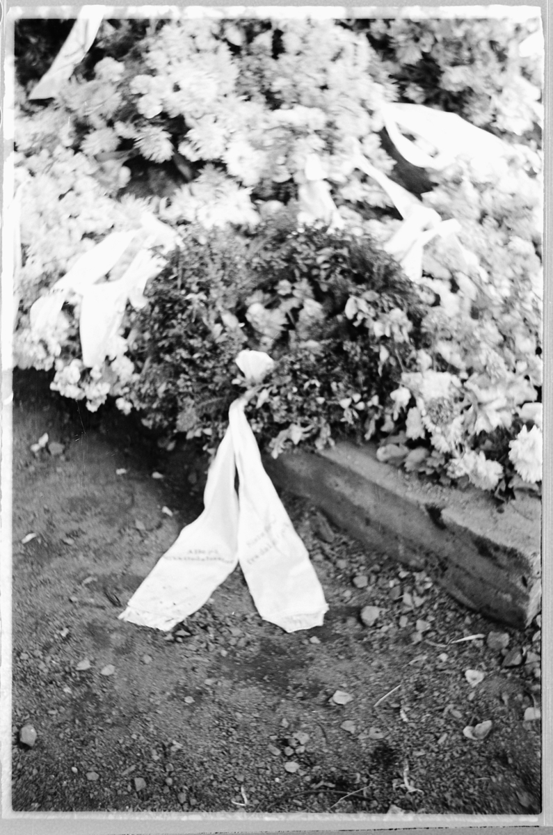 Håkon Prestkværn, En grav med blomsterkranser på en kirkegård.