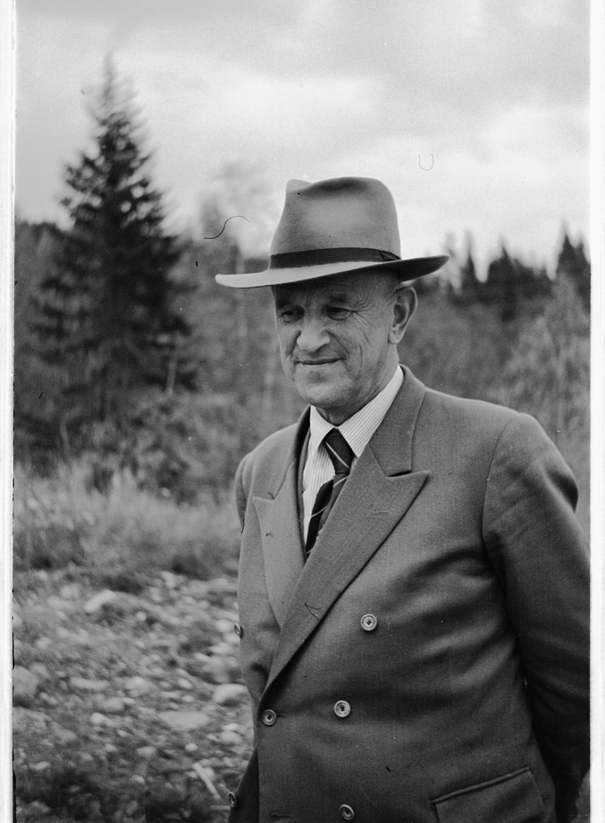Håkon Prestkværn, Eksteriør, skog. Ukjent mann med dress og hatt.