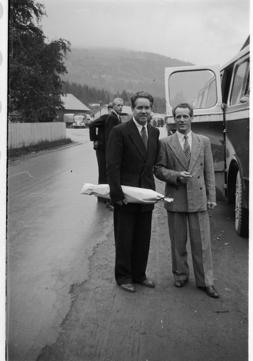 Håkon Prestkværn, To menn i dress ved en buss.