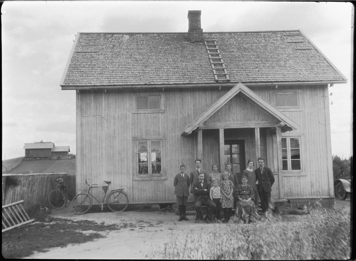 Ole M Martinsen, Ukjent familie ved inngangen til et hus. Sykler inntil husveggen.
