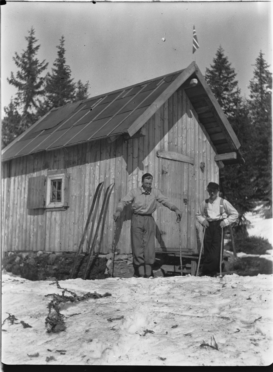 Ole M Martinsen, HYTTE, Solås. To menn gjør seg klar for skitur. Hytta til Ole M. Martinsen (Spånestad) lå på Ruskåsen vest, Løten almenning. Hytta revet 1971. Det ble bygd ny hytte av familien Fuglebrenden på samme sted på 1970-tallet (Sportskapellet).