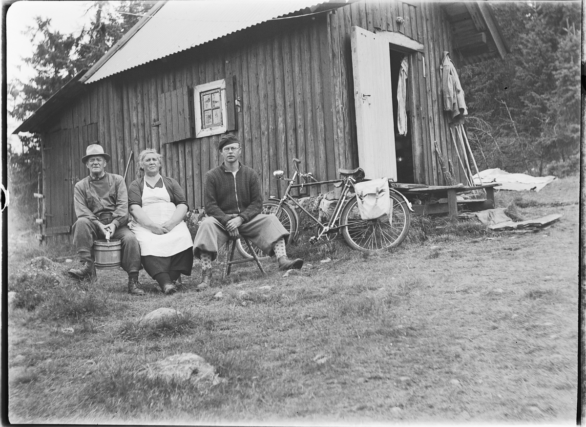 Ole M Martinsen, Hytte, Solås. Ukjente menn og kvinne. Bøtte og sykkel. Hytta til Ole M. Martinsen (Spånestad) lå på Ruskåsen vest, Løten almenning. Det ble bygd ny hytte av familien Fuglebrenden på samme sted på 1970-tallet (Sportskapellet).