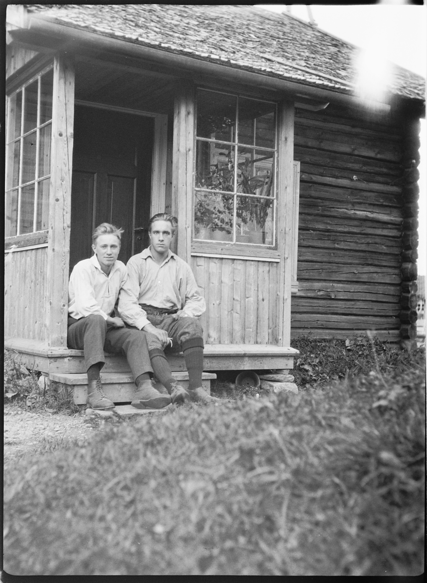 Ole M Martinsen, To menn på trappa ved inngangsdøra til et hus.