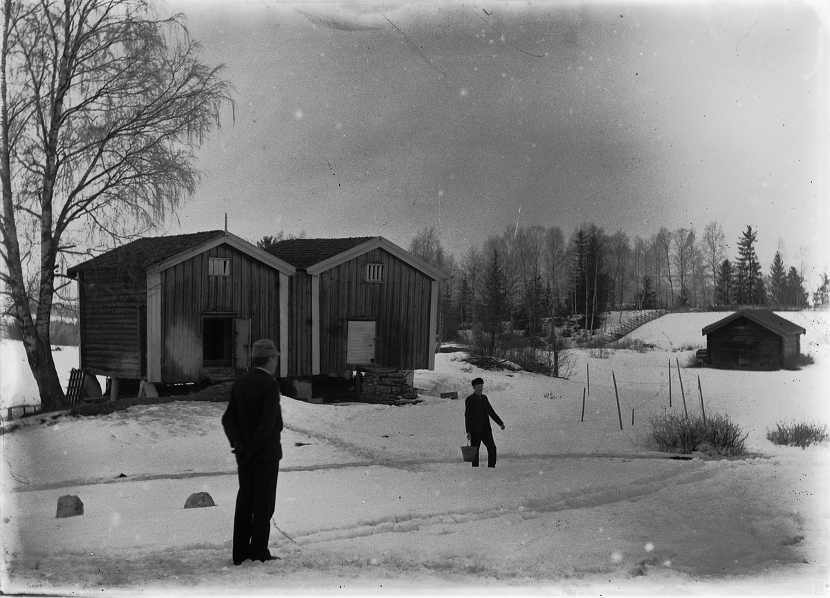 Kristoffer Horne, Eksteriør, gård. To menn foran to stabbur. Herberg på Ring i Ringsaker.