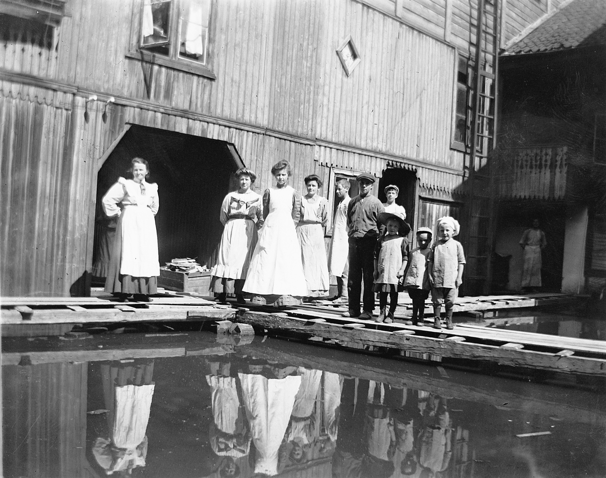 Johs. (Johannes) Johannessen, Folk i bakgården i Strandgata 15 i Hamar, hos baker Johannessen. Storflommen i 1927. Bakermesterfrue Lovise Johannessen til venstre
