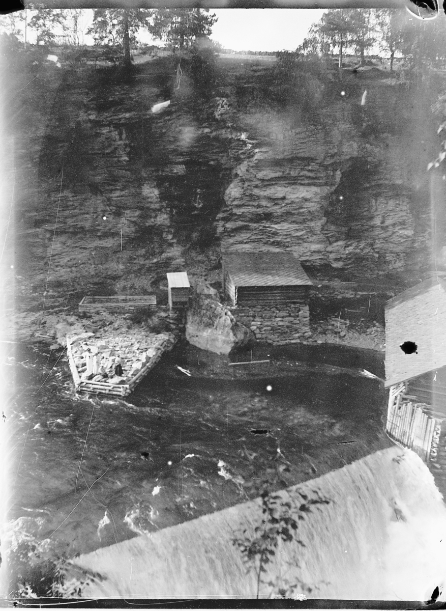 Johs. (Johannes) Johannessen, En tømmerbygning ved en foss.