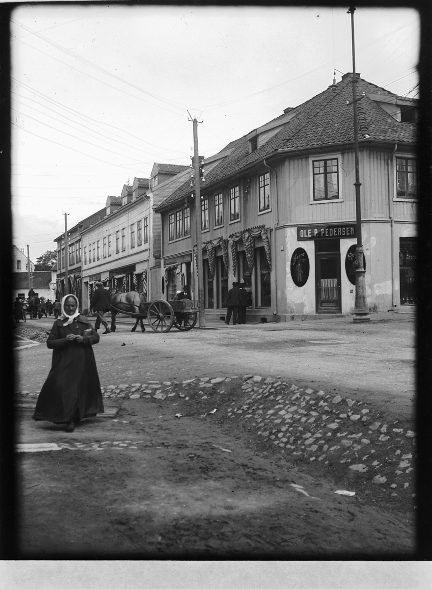 Ragnvald Andersen, Gatelivsbilde. Ole P. Pedersen skredderforretning, Torggata 51, hjørnegård, Hamar.