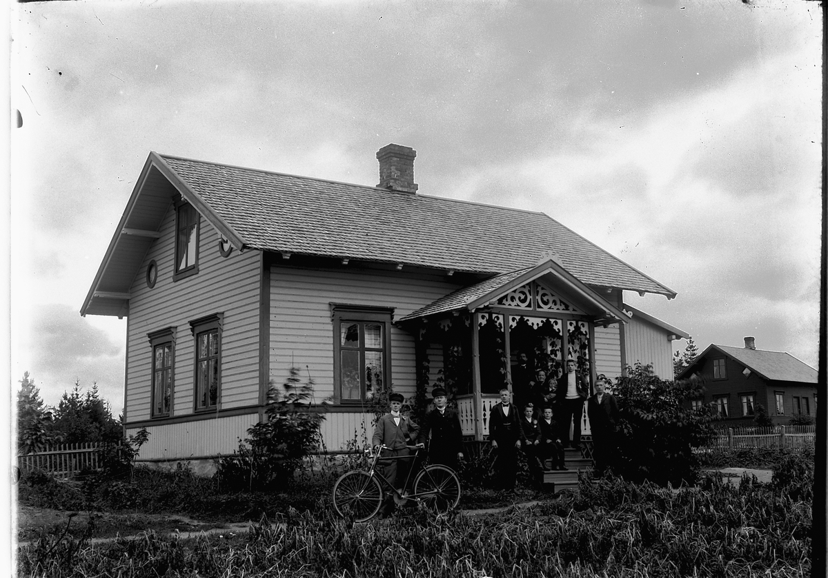 Ragnvald Andersen, Stor gruppe på trappa til et hus. En mann holder en sykkel.
