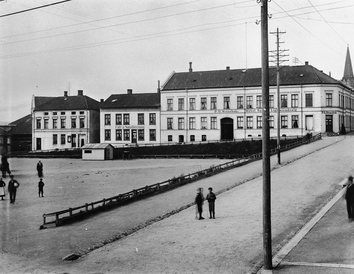 Hans Emil Erichsen, Østre Torg i Hamar med Grønnegata og Håkons Gate. Folk på torget. P.O. Stensbak Møbel Speil & Ligkisteutsalg. Cafe & Spiseforretning.