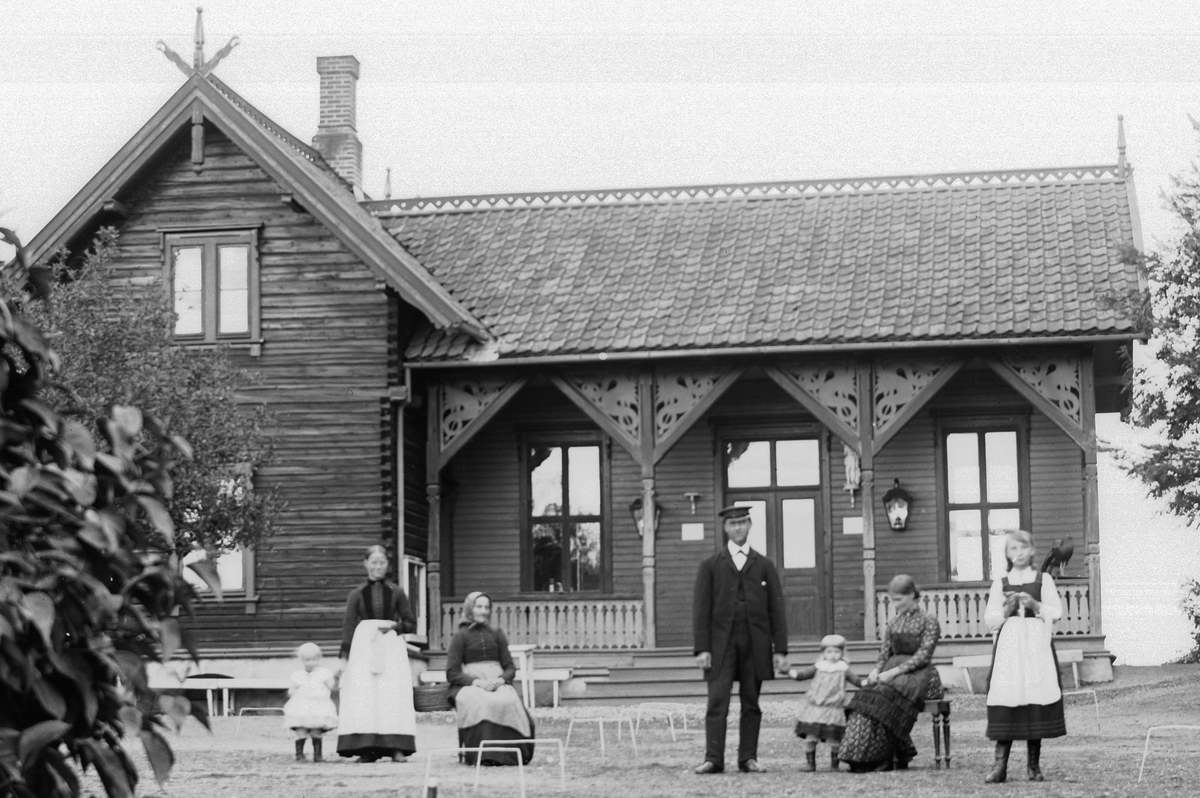 Hans Emil Erichsen, Hamar park. Vaktmesterboligen med voksne og barn utenfor. Tømmerbygning i dragestil. Utsnitt.