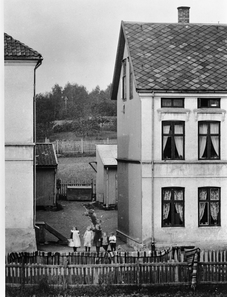 Hans Emil Erichsen, Sverres gate 54-56 i Hamar. Stakitt i forgrunnen. Barn i portrommet.