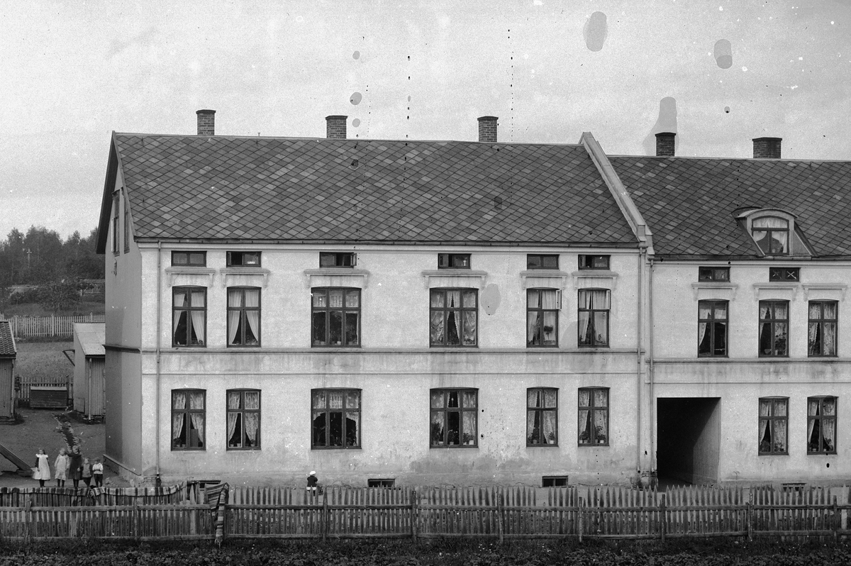 Hans Emil Erichsen, Sverres gate 54-56 i Hamar. Stakitt i forgrunnen. Barn i portrommet.