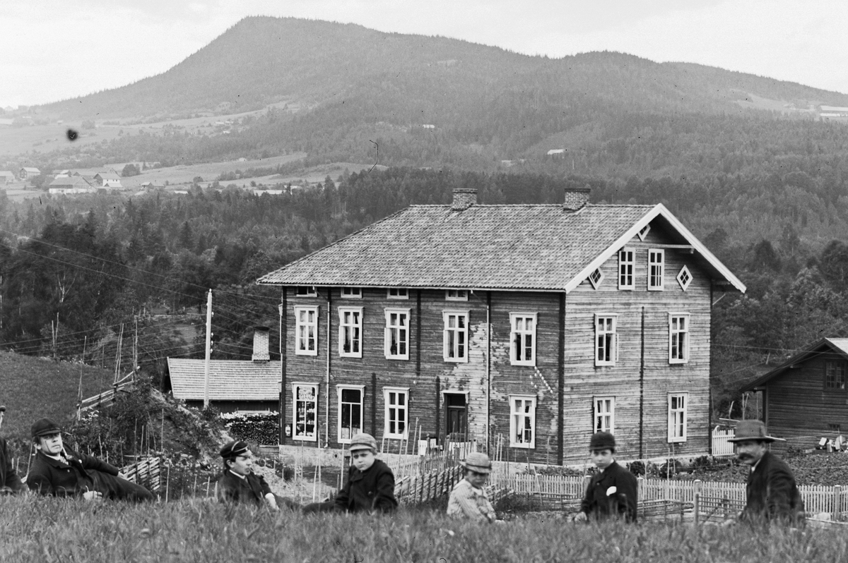 Hans Emil Erichsen, Forretningsgården Finsal i Brumunddal. Kjøpmann Sørlie bygde gården i 1886. Ble overtatt av K. Kolloen før 1900. Senere kjent som Kolloengården. Til høyre i bakgrunnen er Brumunddal Brenneri. Personene på bildet fra venstre Jens Buttekvern f. ca. 1840, student Andreas Erichsen f. 1874, stud. theol.…