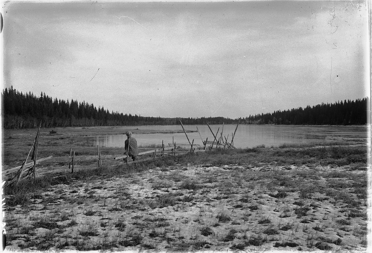 Simen Baardseth, Ukjent mann sitter på et gjerde ved et vann i skogen.