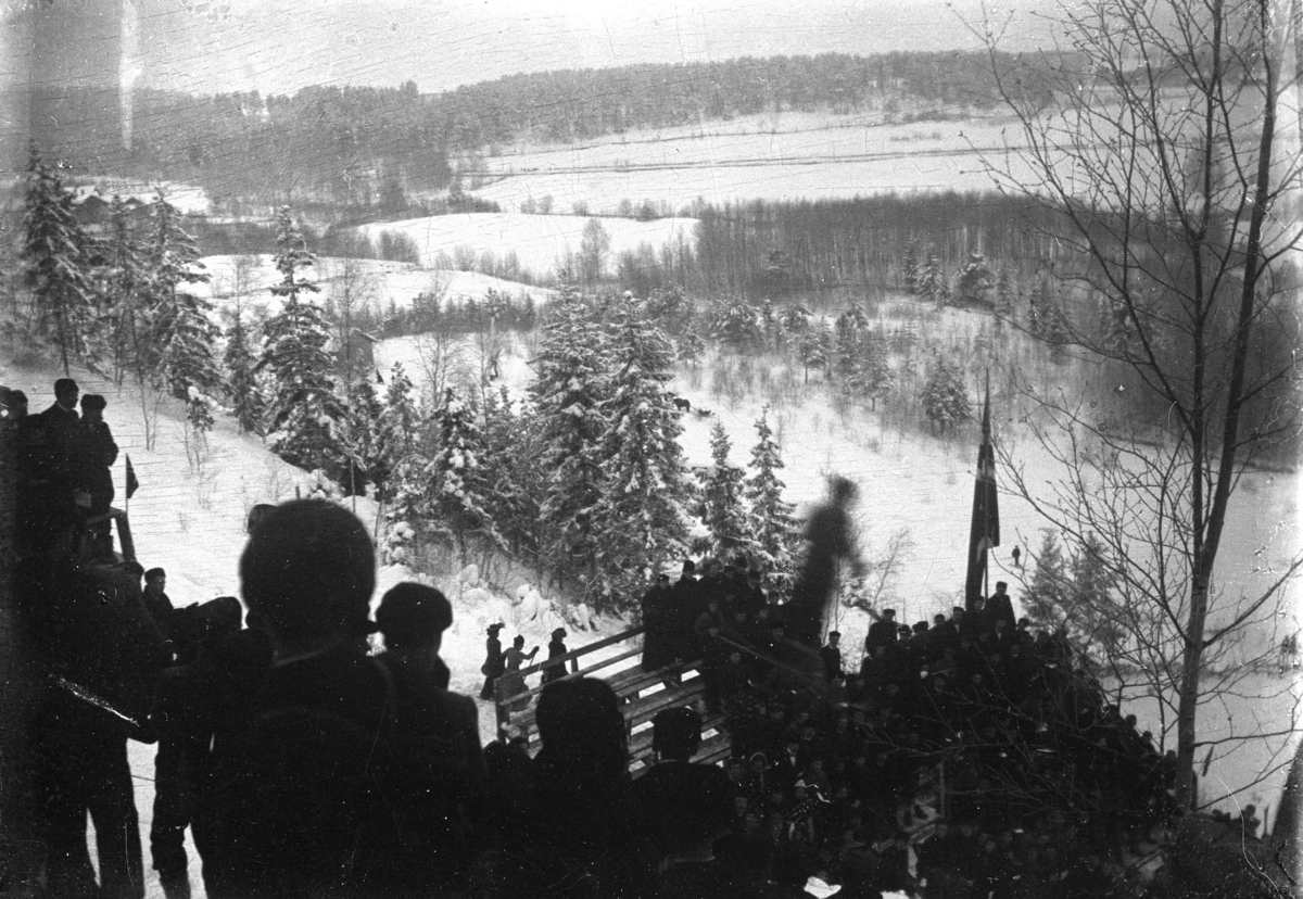 Johannes Larsen Alhaug, Hopprenn i Frambakken, Brumunddal. Publikum ser en skihopper sveve over kulen.