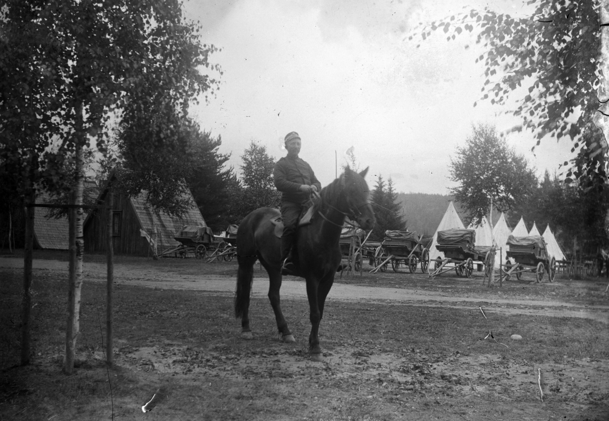 Johannes Larsen Alhaug, En soldat på hesteryggen. Telt og kjerrer i bakgrunnen.