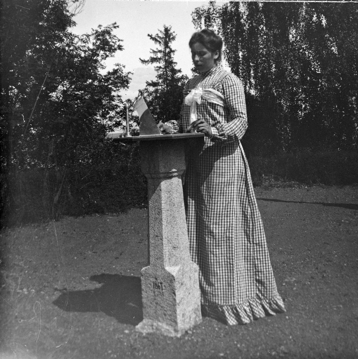 Jacob Tollesen Hoel, Anna Benjamine Hoel f.1872 står ved et solur, konstruert av Jacob Hoel. Hovinsholm gård, Helgøya i Ringsaker. Foto Jacob Hoel.