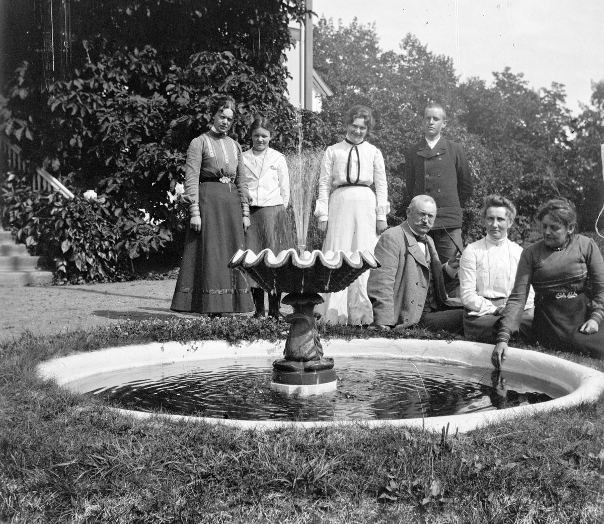 Jacob Tollesen Hoel, Familiegruppe ved fontenen, springvannet, ingen navn kjent. Hovinsholm gård, Helgøya i Ringsaker. Foto Jacob Hoel.