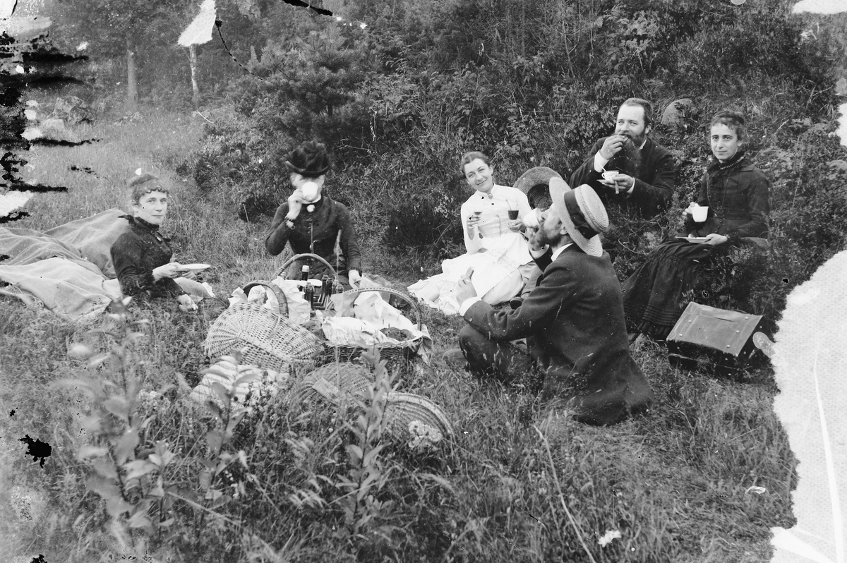 Hans Emil Erichsen, Gruppe ukjente kvinner og menn ute. Kurver med mat og drikke.