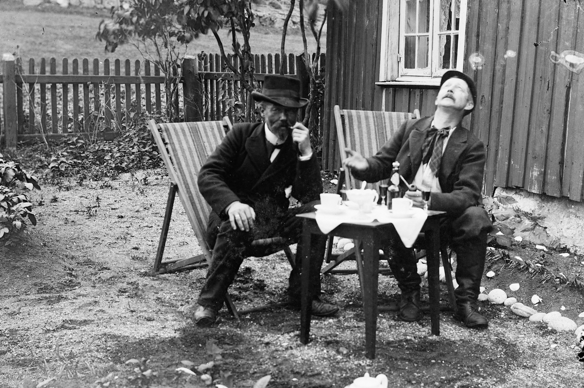 Hans Emil Erichsen, 2 menn ved bord i hagen. Ludvig Skramstad til venstre.