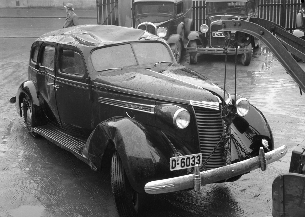 Normann Fotoatelier, Oplandske Auto. Kolisjonskadet bil, D-6033. Hamar. Nash 1938. Registreringsnummer i serien 5000-10000 hørte hjemme i Østerdal politidistrikt. I bakgrunnen fra venstre:Muligens Pontiac 1929-30, Ford A 1930.