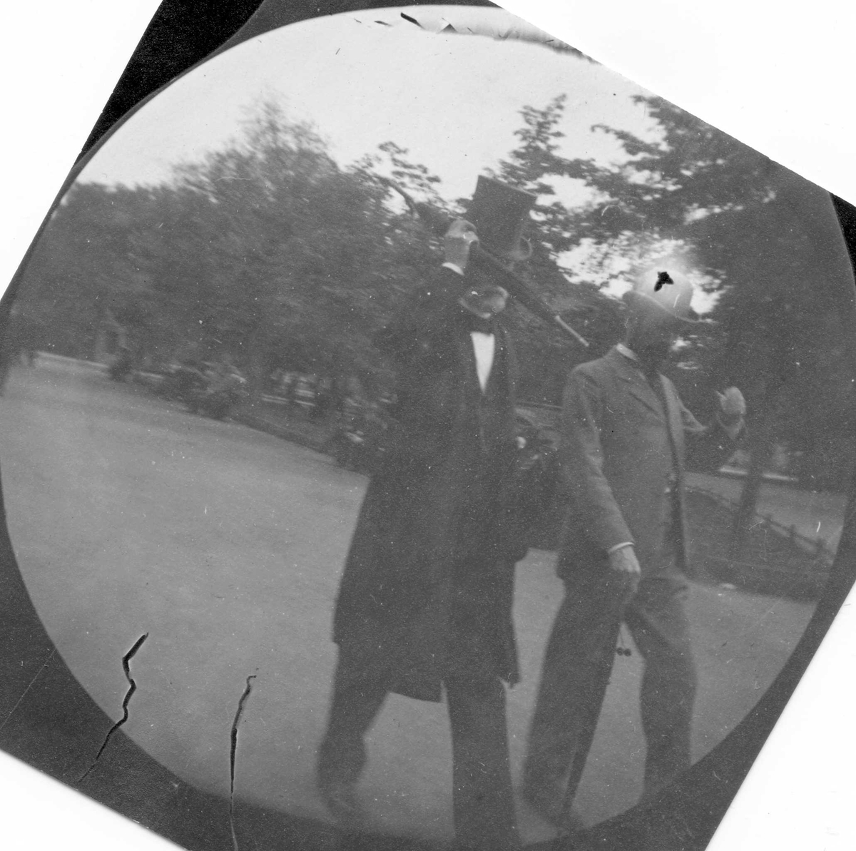 Fredrik Carl Mülertz Størmer, To menn med skjegg, paraply, hatt og flosshatt spaserer i park, Oslo. Overlærer Ottesen, Katedralskolen.