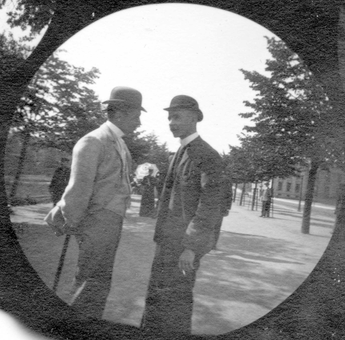 Fredrik Carl Mülertz Størmer, To unge menn står og prater i Studenterlunden, Oslo. Universitetet skimtes mellom trærne. Studenter fra 1892.
