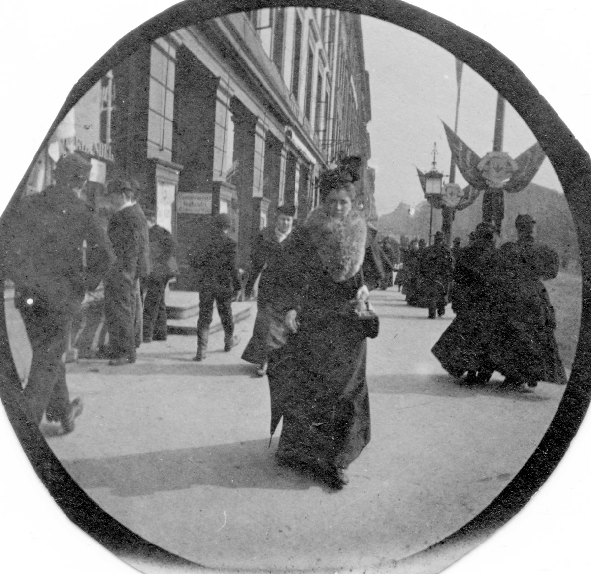 Fredrik Carl Mülertz Størmer, Gatebilde med mange mennsker og flaggdekorasjoner på stolper. Fru Movinkel, født Sverdrup, midt i bildet. Muligens Karl Johans gate, Oslo.