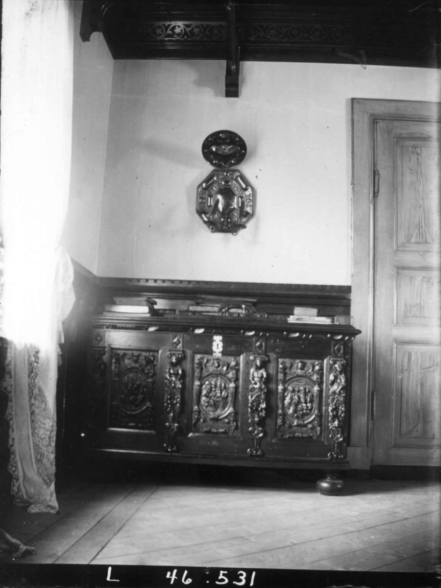 Fredrik Emil Faye, Interiør, Dal gård, Ullensaker. Rom med utskåret kiste, lysskjold på veggen. Fra serie fotografert av kammerherre Fredrik Emil Faye (1844-1903), gårdens eier.