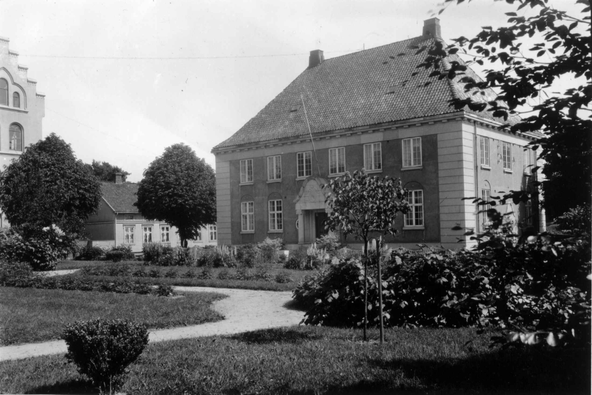 Hermann Christian Neupert, Fredrikstad. 1930. Murbygning omgitt av park med gangveier, trær og busker.