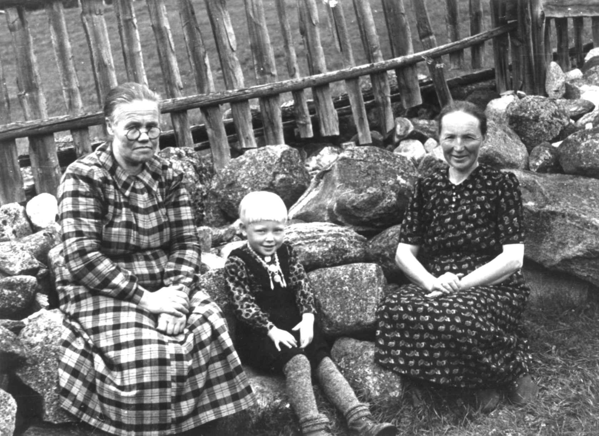 Anna Grostøl, Bråtådal, Skjåk, Oppland 1941. Ragnhild Kårstadlykkjen med datter og søsteren Anne Horte. De sitter på noen steiner ved et gjerde.