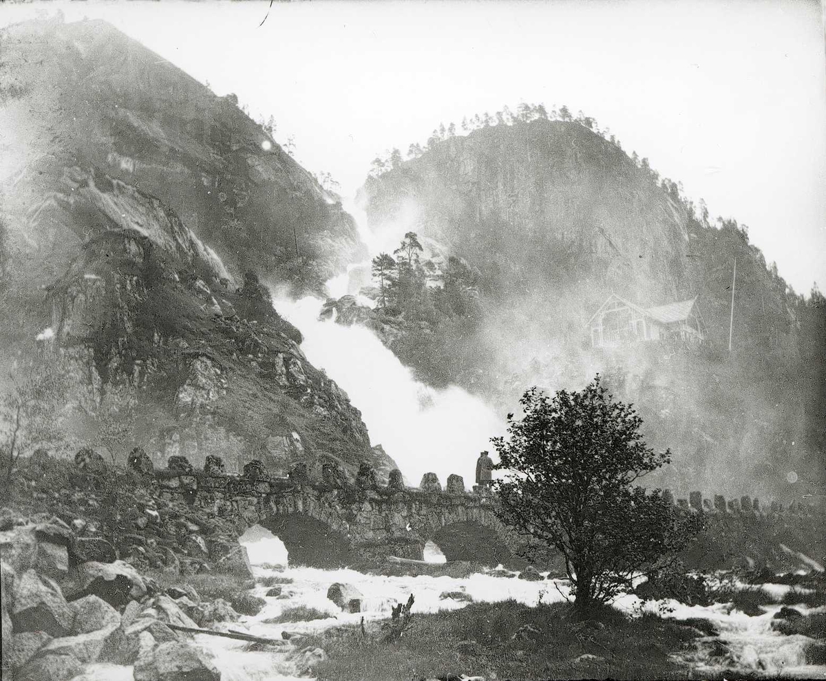 Tom Kent, Gammel steinbru med buer over Låtefoss, Odda. To mennesker på brua.