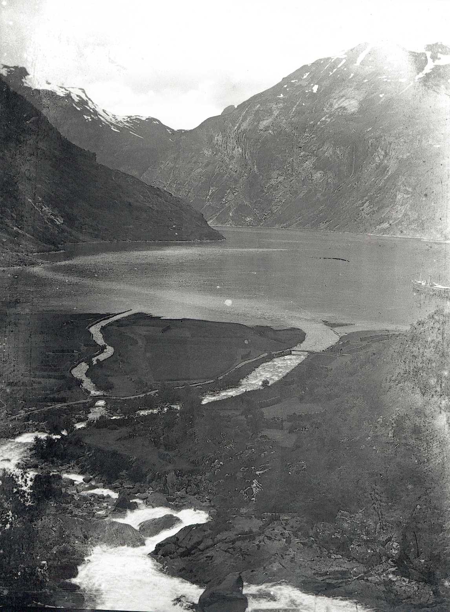 Tom Kent, Elv renner ut i fjord på Stranda, Geiranger. Dampskip ligger på fjorden.