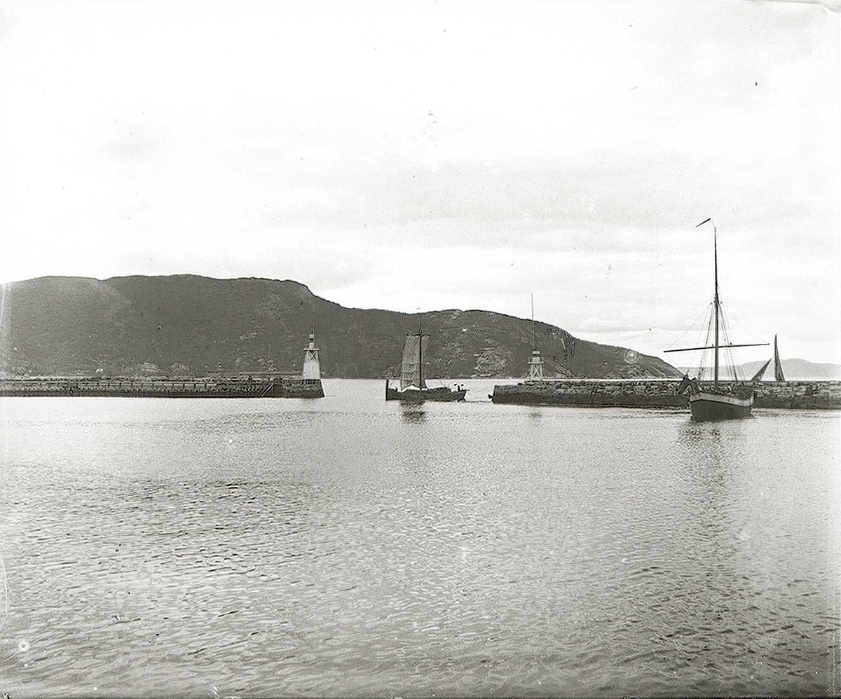 Tom Kent, Molo i fjord. En seilbåt under seil i åpningen og en ligger innenfor.