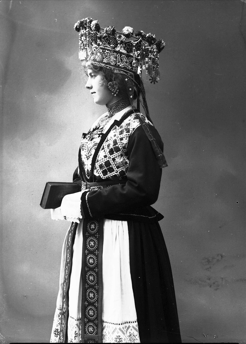Solveig Lund, Studiofotografi av kvinne med brudedrakt og brudekrone. Holder på salmebok/bibel. Stående 3/4 dels utsnitt. Vendt mot venstre. Ser ut mot venstre.