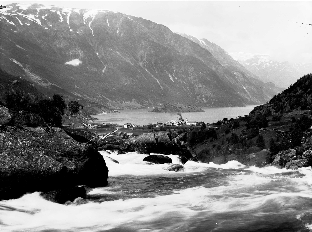 Solveig Lund, Landskapsfotografi fra Odda i Hardanger. I bakgrunnen sees Sørfjorden og i forgrunnen antakelig Opoelva. I midten sees Odda med kirken og Hardanger hotell.