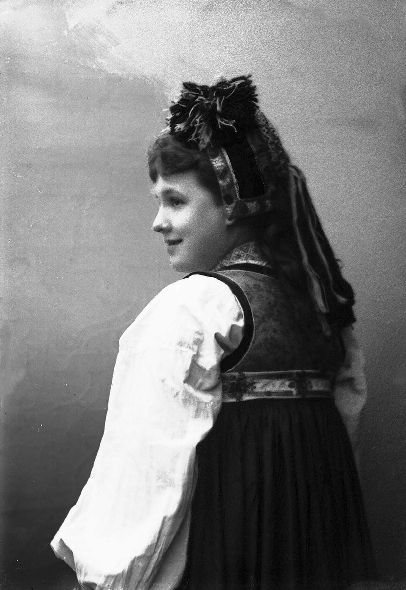 Solveig Lund, Studioportrett av kvinne i drakt og hodeplagg. Avfotografert bakfra.
