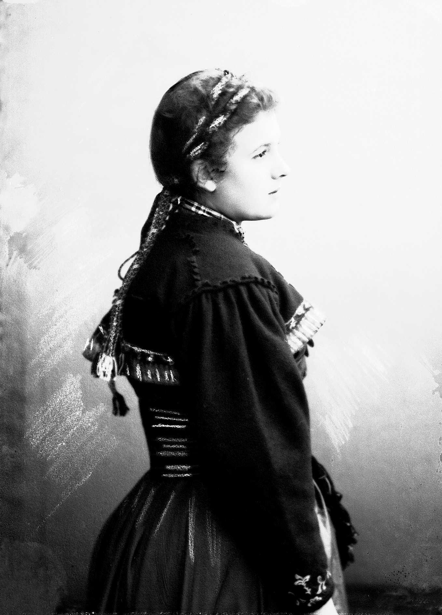 Solveig Lund, Studioportrett av kvinne i drakt og bånd i håret. Avfotografert fra siden.